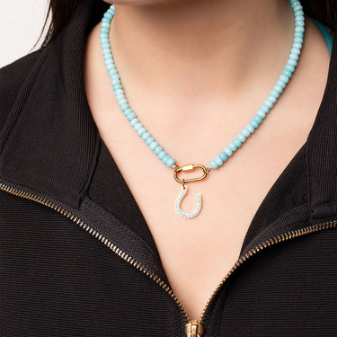 Turquoise beaded necklace with a gold clasp worn by a person in a black jacket.