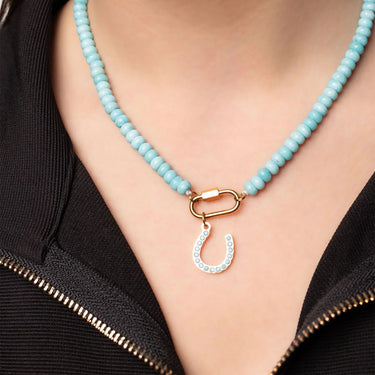 Necklace with turquoise beads and a gold clasp on a person wearing a black top.