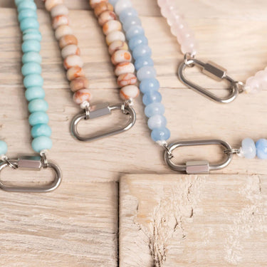Set of beaded keychains with metal carabiners on a wooden surface