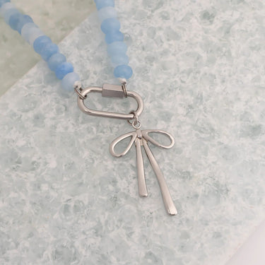 Necklace with blue beads and a silver pendant on a light gray surface