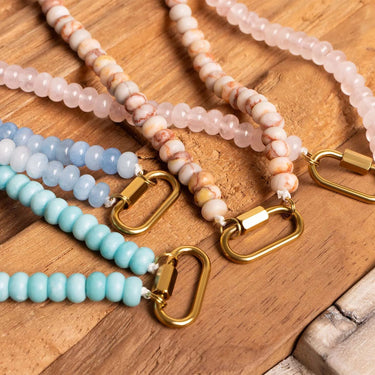 Beaded necklaces with gold clasps on a wooden surface
