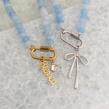 Necklace with 'blessed' charm and bow pendant on a light background