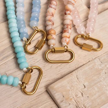Three beaded keychains with gold clasps on a wooden surface