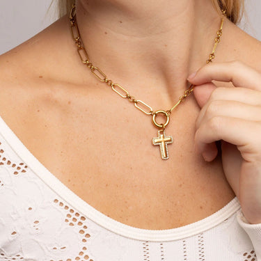 Gold chain necklace with a cross pendant worn by a person