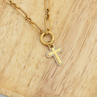 Gold necklace with a cross pendant on a wooden surface