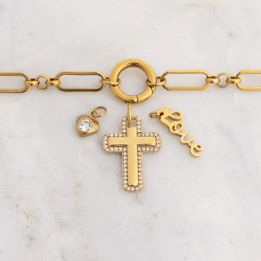 Gold bracelet with cross, heart, and 'love' charm on a marble background