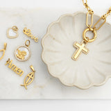 Gold pendants including a cross, fish symbol, and 'Amen' on a marble surface.