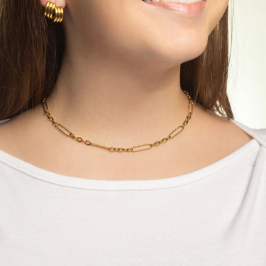 Gold chain necklace worn by a person on a plain background