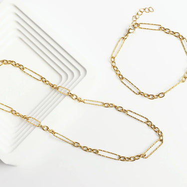 Gold chain necklace on a white surface with a white card underneath