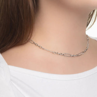 Silver necklace worn by a person on a plain background