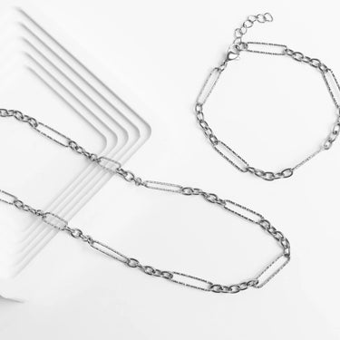 Silver chain necklace and bracelet on a white surface