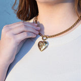Person wearing a gold necklace with a heart-shaped pendant