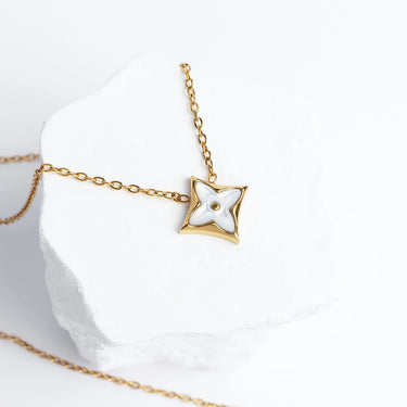 Gold necklace with a star-shaped pendant on a white background