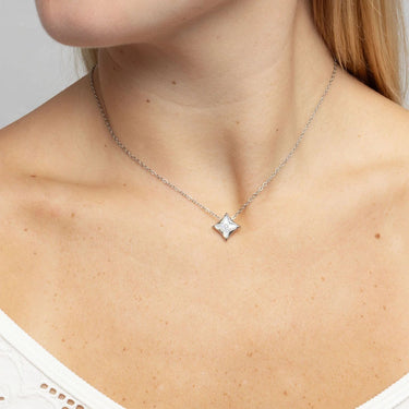Silver necklace with a star-shaped pendant on a person's neck