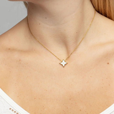 Gold necklace with a star-shaped pendant worn by a person