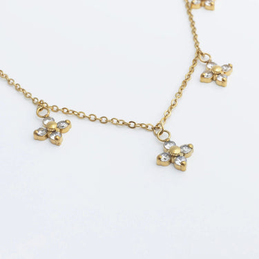 Gold necklace with clover-shaped pendants on a white background