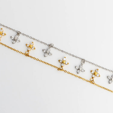 Two gold and silver necklaces with floral pendants on a light gray background