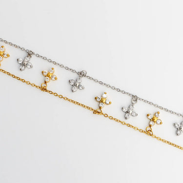 Two gold and silver necklaces with floral pendants on a light gray background