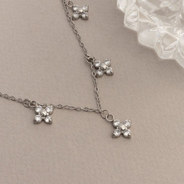 Silver necklace with floral pendants on a beige background