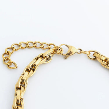 Gold chain bracelet on a light gray background
