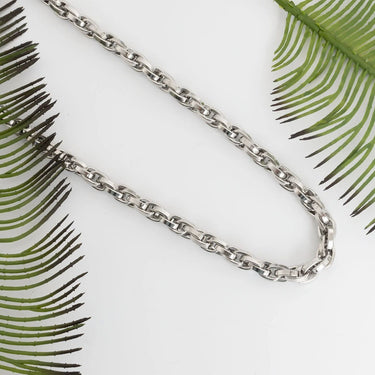 Silver chain necklace on a white background with green leaf patterns