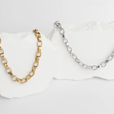 Gold and silver chain necklaces on a white surface