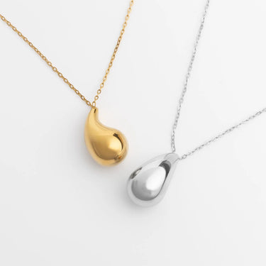 Gold and silver teardrop-shaped pendants on chains against a white background