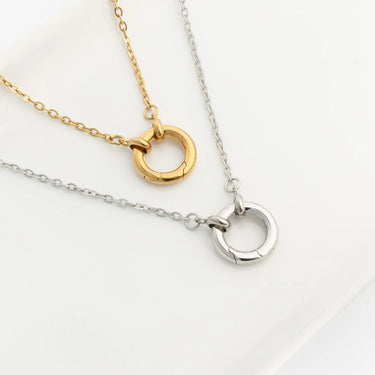 Two necklaces with circular pendants, one gold and one silver, on a light background.