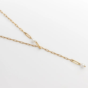 Gold chain necklace with a single pearl on a light gray background