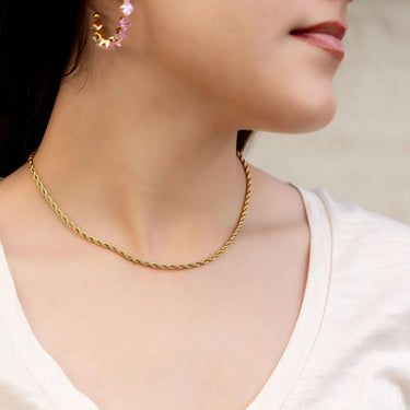 Gold necklace worn by a person with a neutral background