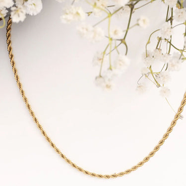 Gold chain necklace on a light background with white flowers