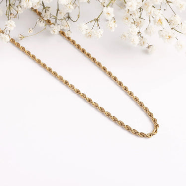 Gold chain necklace on a white background with small white flowers
