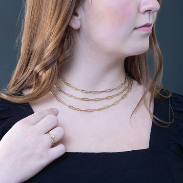Woman wearing a gold necklace with a plain background