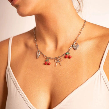 Necklace with cherry and bow charms worn by a person