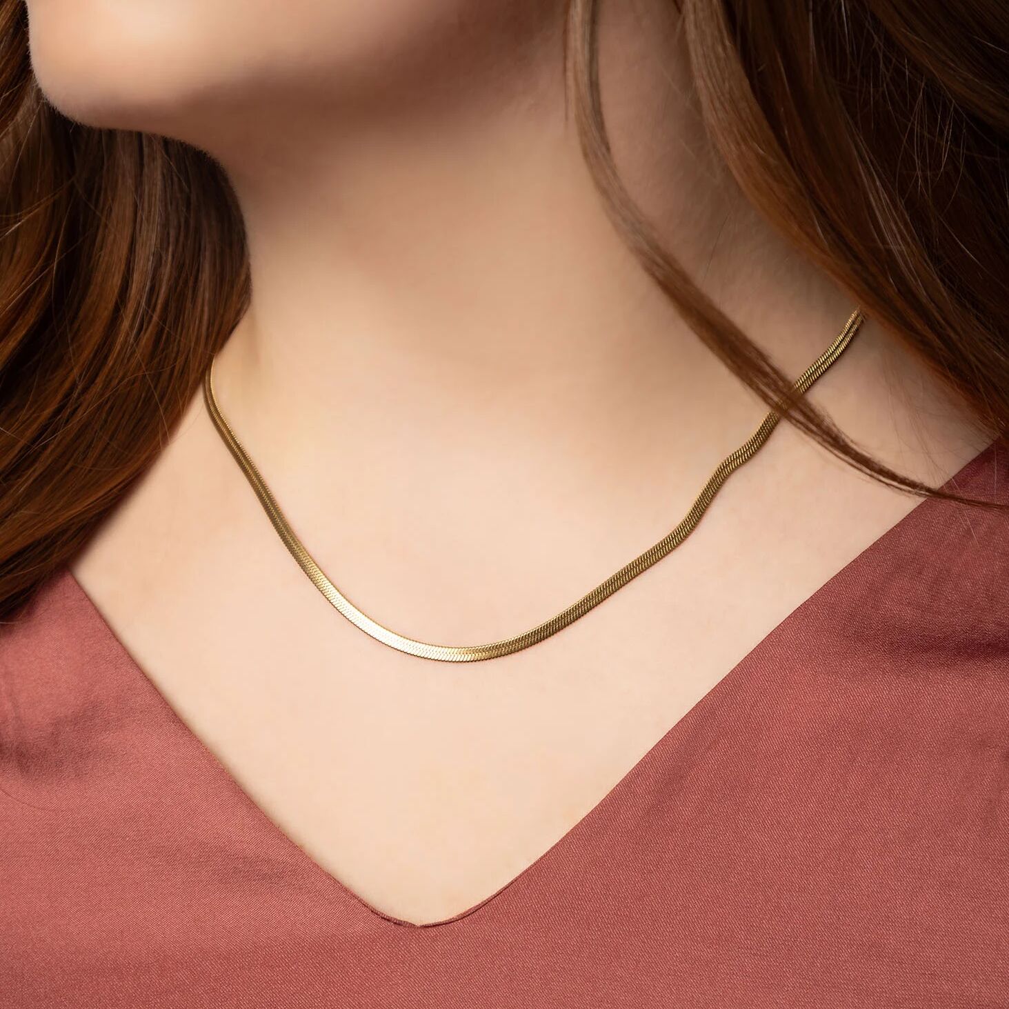 Gold necklace worn by a person with a blurred background