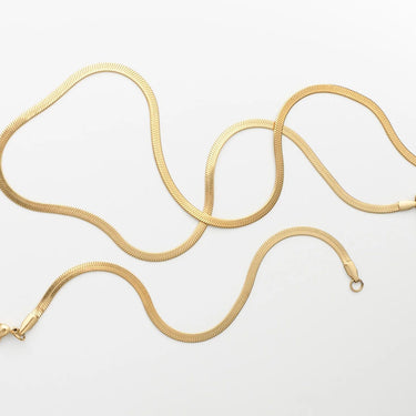 Gold snake chain necklace on a light gray background