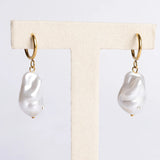 Pair of pearl earrings on a display card with a neutral background