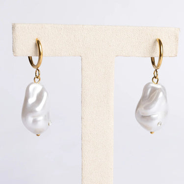 Pair of pearl earrings on a display card with a neutral background