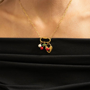 Gold necklace with a pendant featuring three small balls on a black background