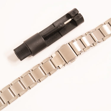 Metal watch strap with black tool on a white background