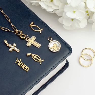 Gold religious pendants on a navy blue leather cover with white flowers in the background
