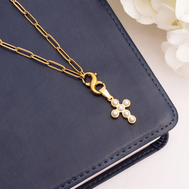 Gold cross necklace with pearls on a navy blue surface