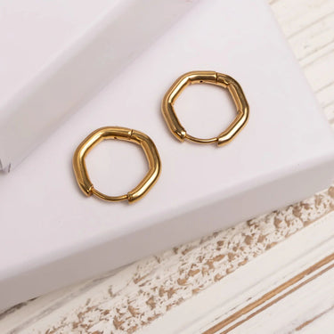 Gold hoop earrings on a textured white surface