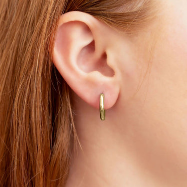 Gold hoop earring worn by a person with red hair