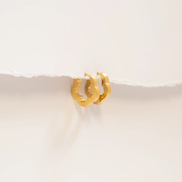 Gold hoop earrings on a light beige surface
