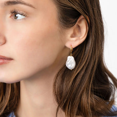Close-up of a woman wearing a pearl earring with a blurred background