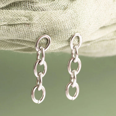 Pair of silver chain earrings on a light fabric background