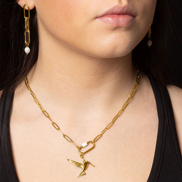 Gold chain necklace with a bird pendant worn by a person