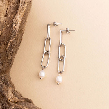 Silver chain earrings with pearl drops on a beige background