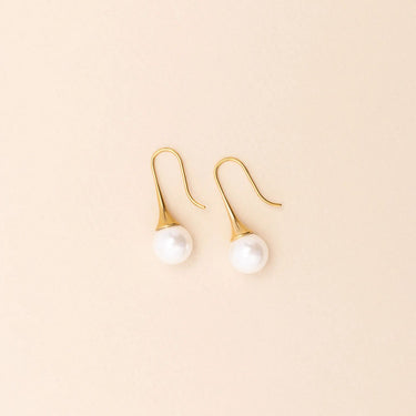 Gold earrings with pearl drops on a beige background